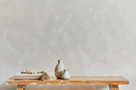 Stylish composition of living room interior with copy space, bench in retro style, clay vases and crockery. Rustic inspiration. Summer vibes. Beige wall. Template.の写真素材