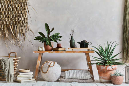 Stylish composition of cozy living room interior with copy space, bench in retro style, clay vase, crockery, straw wall decoration and textiles. Rustic inspiration. Summer vibes. Beige wall. Template.の写真素材