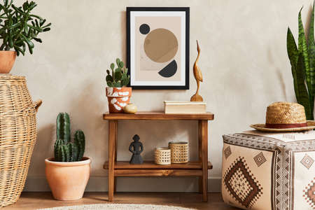 Creative composition of stylish living room interior with mock up poster frame, wooden shelf, pouf, cacti and personal accessories. Plant love and nature concept. Template.の写真素材