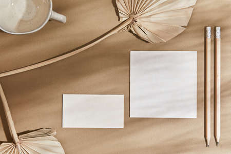 Flat lay creative interior composition with mock up visit cards, textile, pencil, rocks, wood,...