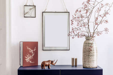 Stylish living room interior with mock up poster frames, navy blue commode, book, decoration and elegant personal accessories in modern home decor. White wall. Template.の写真素材
