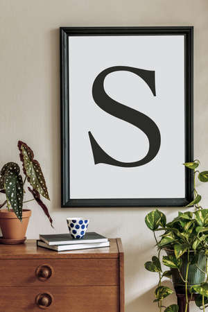 Vintage interior design of living room with design retro wooden commode, plants, cacti, books, accessories and black mock up poster frame on the beige wall. Stylish home decor. Template.の写真素材
