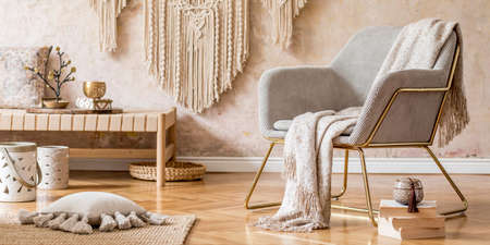 Stylish oriental living room with design armchair, beautiful macrame, carpet, decorations and...