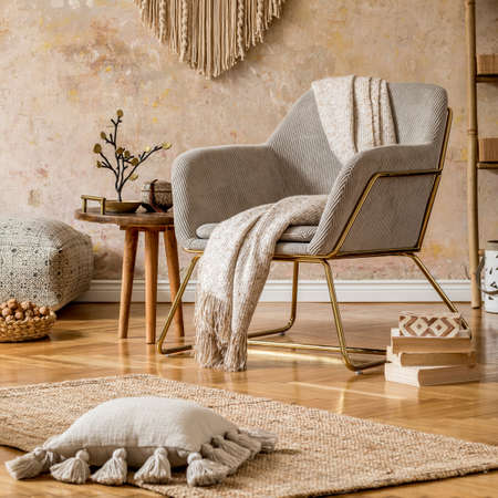 Stylish oriental living room with design armchair, beautiful macrame, wooden ladder, plant, decoration, carpet, coffee table, book and elegant personal accessories in wabi sabi concept.の写真素材