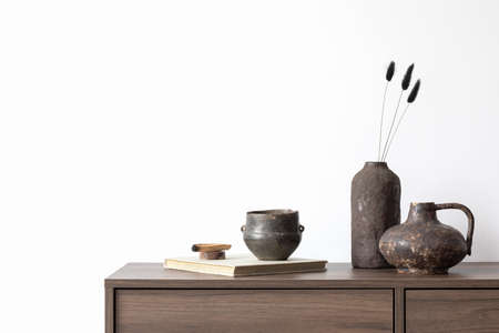 Stylish living room interior composition with brown wooden commode, candle and small home decorations. White wall. Copy space. Template.の写真素材