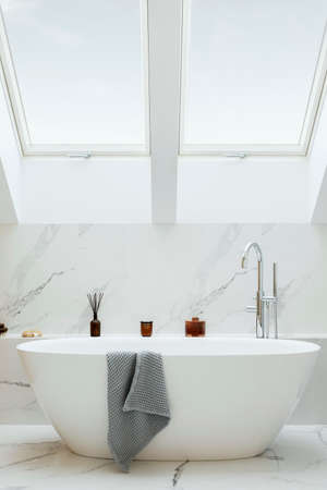 Stylish bathroom interior design with marble panels. Bathtub, towels and other personal bathroom...
