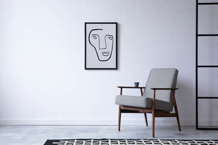 Minimalistic loft interior composition with retro design armchair and mock up poster frame. Copy...