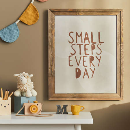 Stylish scandinavian newborn baby room with brown wooden mock up poster frame, toys, plush animal and child accessories. Cozy decoration and hanging cotton flags on the beige wall. Template.の写真素材