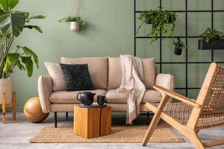 The stylish composition at living room interior with design beige sofa, black coffee table, plants...