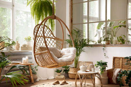 The stylish boho composition with changing swing, window, commode and wooden bench. Beige carpet with brown slippers. White wall. Template.の写真素材