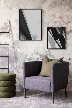 Loft and industrial living room interior with mock up poster frame, stylish gray armchair, bottle...