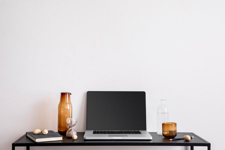 Interior design of minimalist stylish office interior with copy space, white wall, laptop, black desk, glass bottle, book and classic personal accessories. home dÃ©cor. template.の写真素材