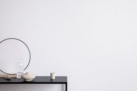 Aesthetic interior of living room with copy space, white wall, black table, candlestick, glass bottle, round decoration and elegant personal accessories. Stylish home decor. template.の写真素材