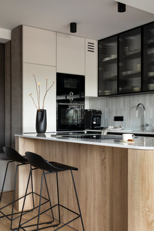 Modern composition of kitchen space with design kitchen island, black hookers, gray table, black vase with dried flowers, furnitures, and elegant personal accessories. Stylish home decor. template.の写真素材