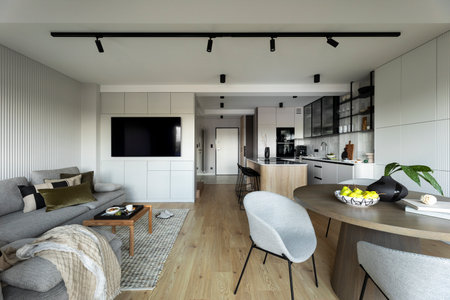 Interior design of harmonized gray apartment. Round table with gray chair, dark vase with leaves,...