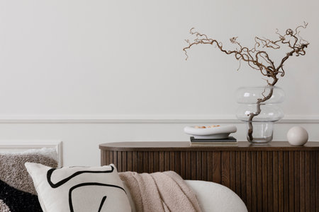 Minimalist composition of living room interior with wooden sideboard, glass vase with branch, bowl, ball sculpture, white sofa, and personal accessories. Home decor. Template.の写真素材