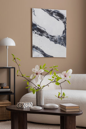 Cozy composition of spring living room interior with mock up poster frame, boucle sofa, vase with magnolia, wooden coffee table, books, white lamp and personal accessories. Home decor. Template.の写真素材