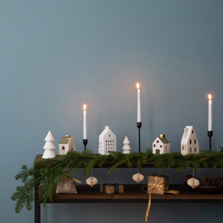 Minimalist composition of christmas interior with copy space, wooden console with sprace, christmas balls, candle with candlestick, blue wall, gifts and personal accessories. Home decor. Template.の写真素材