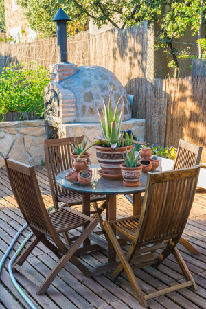 Table and chairs in the wooden terrace of the gardenの写真素材