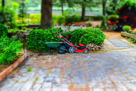 A mower and a wheelbarrow in the gardenの写真素材