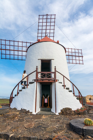 Young woman standing on a traditional Spanish windmill in Lanzarote, Canary Islands, Spainの写真素材