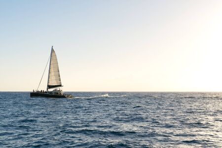 Sailboat sailing over the sea at sunsetの写真素材