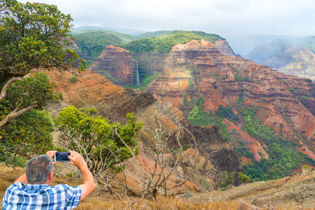 Tourist enjoying Waipo'o Falls in Waimea Canyon, Kauai Island, Hawaiiの写真素材