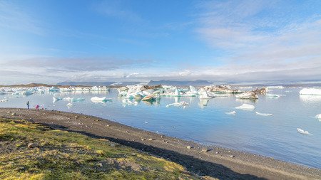 Couple enjoying the view of Icebergs in Jokulsarlon glacial lake, Icelandの写真素材