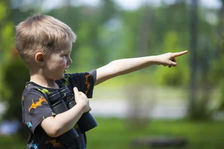 Young boy in a field looking through binocularsの写真素材