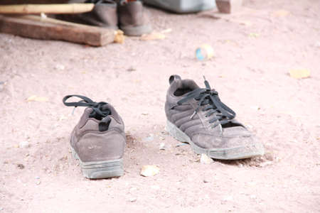 Old dirty sneaker discarded on soil.