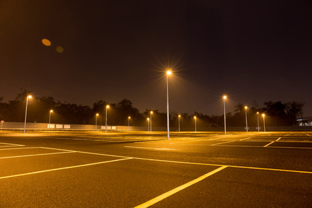 Empty outdoor car park at night shined with street lamps.の写真素材