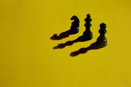 Three chess casting shadow on yellow backgroundの写真素材