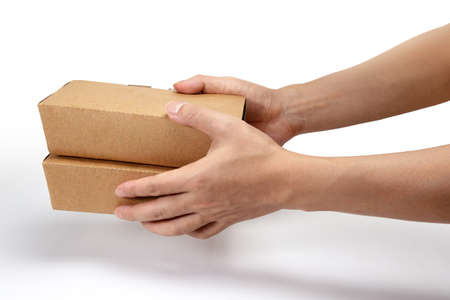Hand giving takeaway cardboard food boxes to customer isolated on white