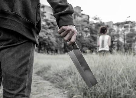 Murderer ready to attack his victim with a knife on grass outdoorの写真素材
