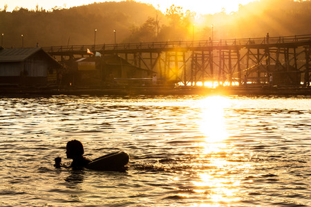 Low key of silhouette children swimming in the river with sunset light. Summer background.の写真素材