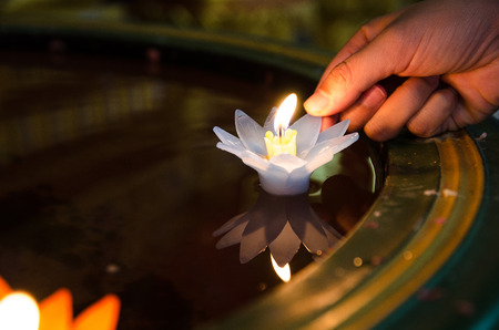 People hand release Lotus flower candle lighting and floating in the water with peaceful and hopeful. faith and belief concept.の写真素材