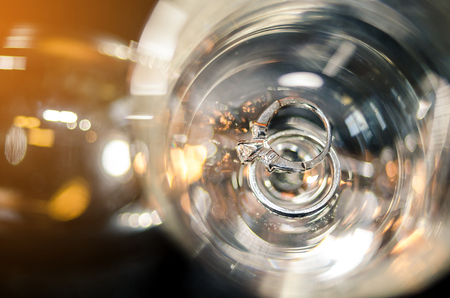 Selective focus of wedding diamond rings in champagne cup with sun lightの写真素材
