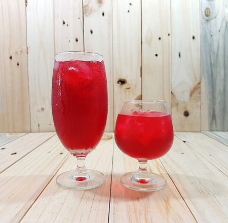 Couple glass of red color water wirh ice on wooden background with copy spaceの写真素材