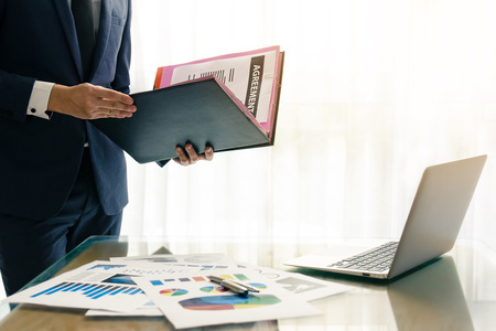 Businessman holding folder with documents of ageement and concentrate to reading in officeの写真素材