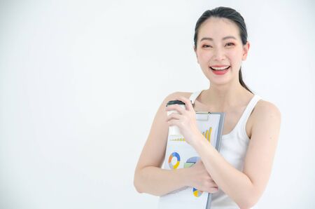 Pretty young asian business woman holding a cup of coffee and document files. Isolated Studio portrait on white backgroundの写真素材