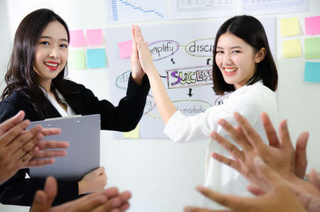 Business people giving each other high five and clapping. Business team celebrating success. Corporate group of employees congratulating each other on the victoryの写真素材