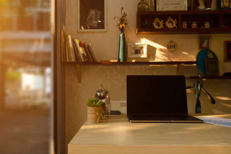 Work desk in home office  laptop/notebook computer, clock, calculator, report paper, cactus tree and cup of coffee in morning. Work hours & lifestyle business. Work from homeの写真素材