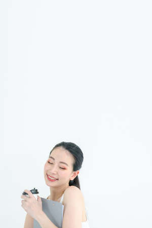 Young asian secretary in casual wear and coffee mugs on hand. Happily embracing the document report. Smiling on work days. Copy space for label text using in advertisement bannerの写真素材
