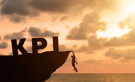 Silhouette Young businessman climbing the mountain to achieve KPI with sky, clouds and sunset background. Fight for reach key performance indicator in summer with copy space for label text bannerの写真素材