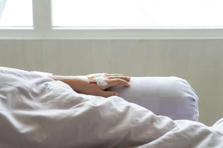 Close up of woman hand with saline intravenous sleeping rest for convalesceat at patient's bed in hospitalの写真素材