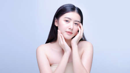 Asian woman beauty shot with half naked isolated on blue background with clean fresh skinの写真素材