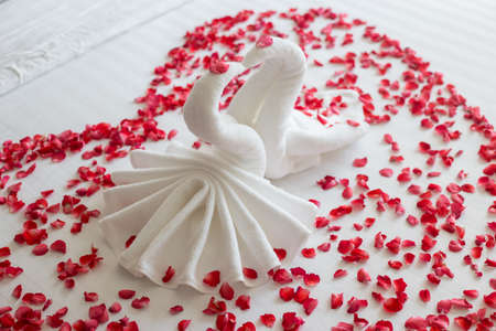 swans made from towels are kissing on honeymoon white bed.の写真素材