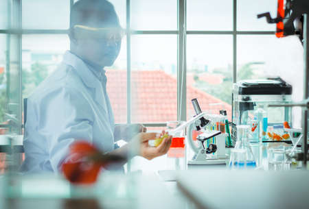 Blurred of asian man scientist in the laboratory dropping the liquid from the beaker to test tube...