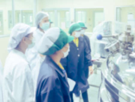 Blurred of scientist, doctor, pharmacist, production team and lab team in gown training instruction to use the mixing and filling machine in the cosmetic plant (site) or drug site with the intentionの写真素材