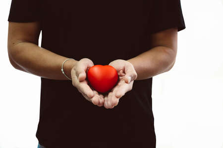 Man in black t-shirt holding red heart in his hand, copy space for text and isolated on white backgroundの写真素材